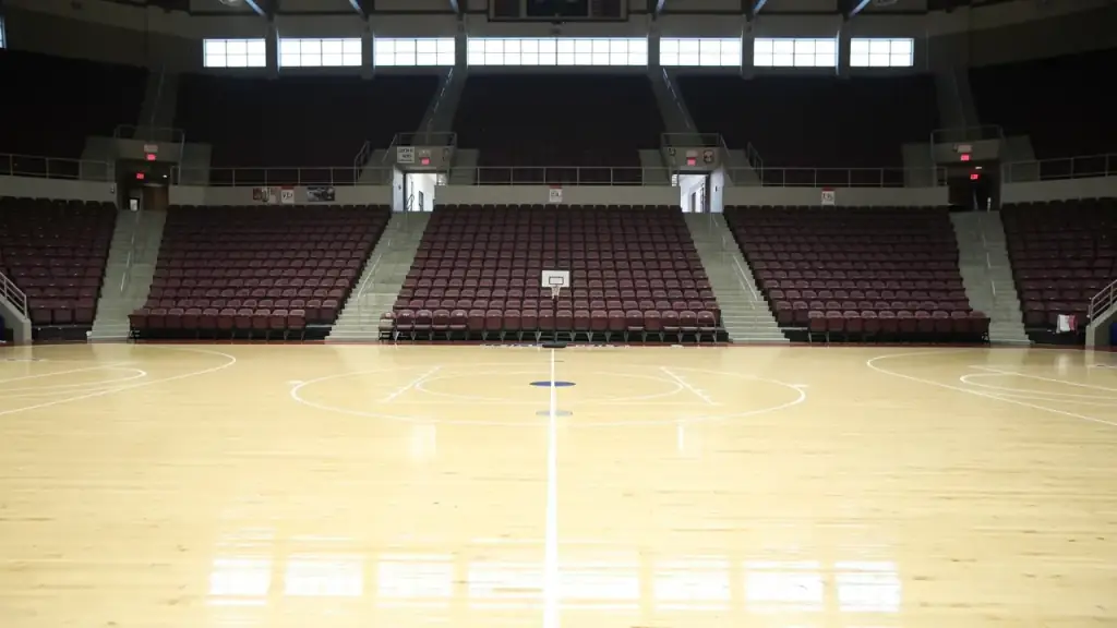 An empty college basketball arena before doors open, the hardwood court under the lights